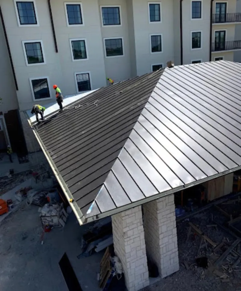Crew installing standing seam metal roof panels on a commercial project in Wakefield